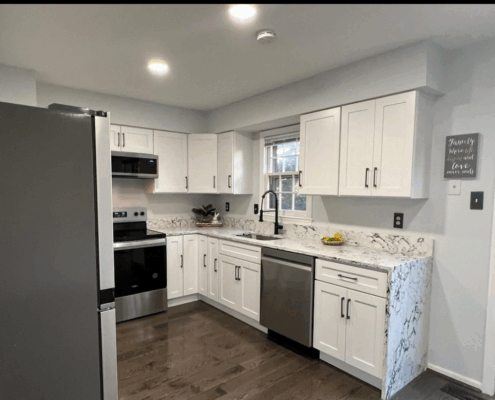 Modern kitchen renovation with white cabinets and marble countertops