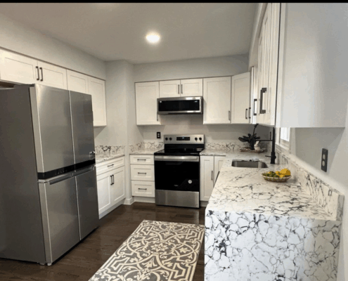 Modern kitchen renovation with white cabinets and marble countertops